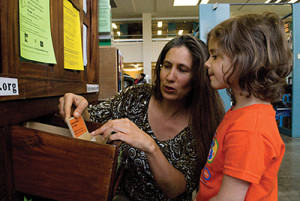 Rebecca Newburn helps a young patron explore the Richmond Grows Seed Lending Library in Richmond, California.