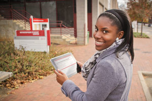 North Carolina State University student Tova Williams uses a tablet to tour campus with an eye toward African-American history at the university. Williams is using an app called Red, White, and Black, which started as a collaboration between NCSU’s Digital Library Initiative, the tour’s creators, and the library’s special collections. Photo: Charles Samuels, NCSU Libraries
