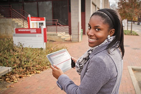 North Carolina State University student Tova Williams uses a tablet to tour campus with an eye toward African-American history at the university. Williams is using an app called Red, White, and Black, which started as a collaboration between NCSU’s Digital Library Initiative, the tour’s creators, and the library’s special collections. Photo: Charles Samuels, NCSU Libraries