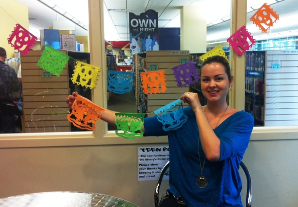 Julie Fuller, young adult librarian at Alvin Sherman Library in Fort Lauderdale, Florida, poses with the papel picado Hispanic folk art teens created at a September 27 program. The adolescents learned how to cut the intricate designs from Nova Southeastern University professor Tennille Shuster.