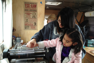 Two participants at Denver Public Library's Community Learning Plazas create a monoprint on a traveling printing press studio.