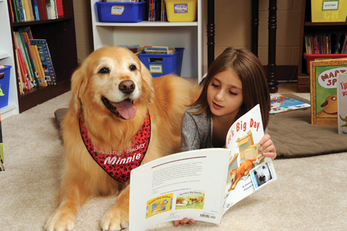 A girl reads to Minnie from K9 Reading Buddies of the North Shore.
