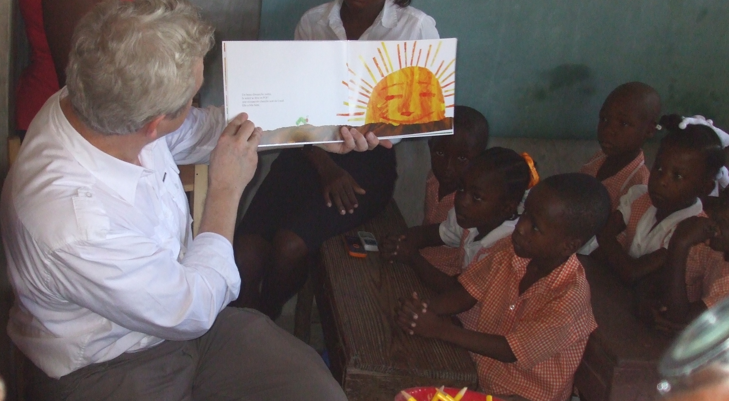 Kindergarteners listen attentively as a visitor reads “La Chenille Qui Fait Des Trous” at the elementary school in Petit-Goâve.