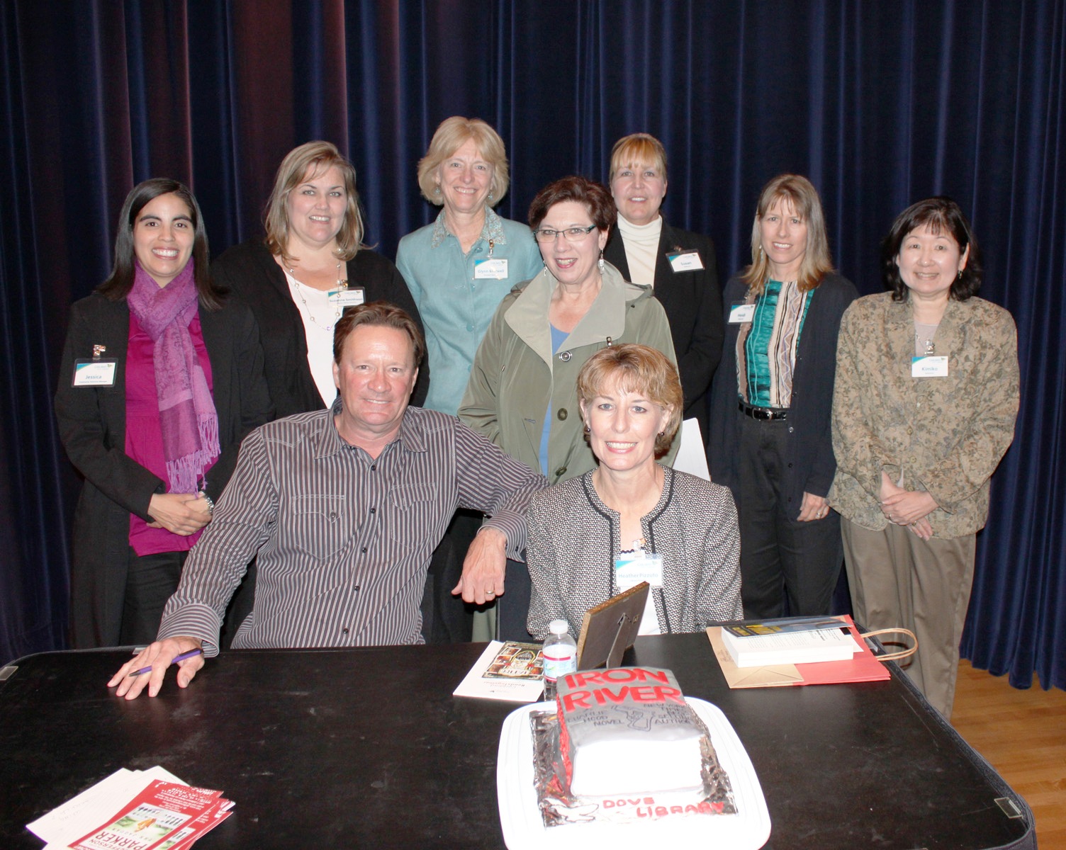  Author T. Jefferson Parker (seated left) joins staff from Carlsbad (Calif.) City Library after a talk about his book Iron River, also depicted in a book cake, during the 8th Carlsbad Reads Together event April 14.