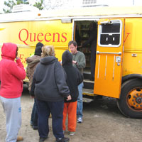 Matt Allison of Queens Library stands outside the library's Book Bus, brought to the Rockaway Peninsula November 2 once emergency crews had cleared roads of sand dunes and storm-strewn boats, to hand out FEMA application information to residents in need. Photo courtesy of Queens Library