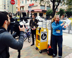 Lauren Comito (center) and Christian Zabriskie (right) of Urban Librarians Unite being filmed during a street storytime
