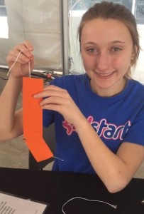 A Girl Start representative shows off the robot arms of paper and string used for building.