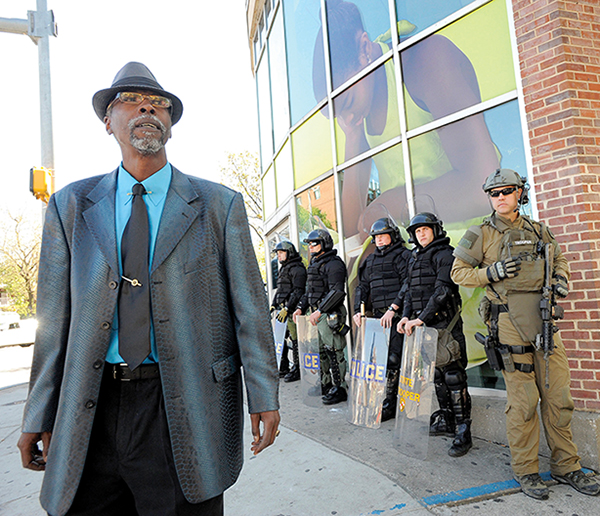 Baltimore resident Kevin Eaton walks past the Enoch Pratt Free Library at Pennsylvania Avenue on April 29 as police were stationed against many city buildings and on the streets.