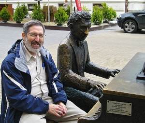 Sapon-White sits next to a bronze statue of pianist Arthur Rubenstein in Łódz, Poland. Photo: Richard E. Sapon-White