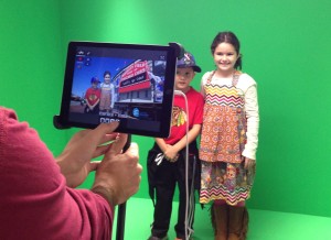 Digital Services Assistant Srdjan Vasilic takes a photo of two patrons in front of the green screen in Niles Public Library's Creative Studio.