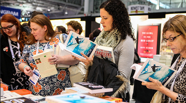 Alison Griffin (middle), Vancouver, Canada, looks at books in the exhibit hall along with other attendees.