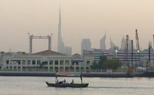 Dubai Creek with traditional water taxi and Burj Khalifa, the tallest building in the world, in background.