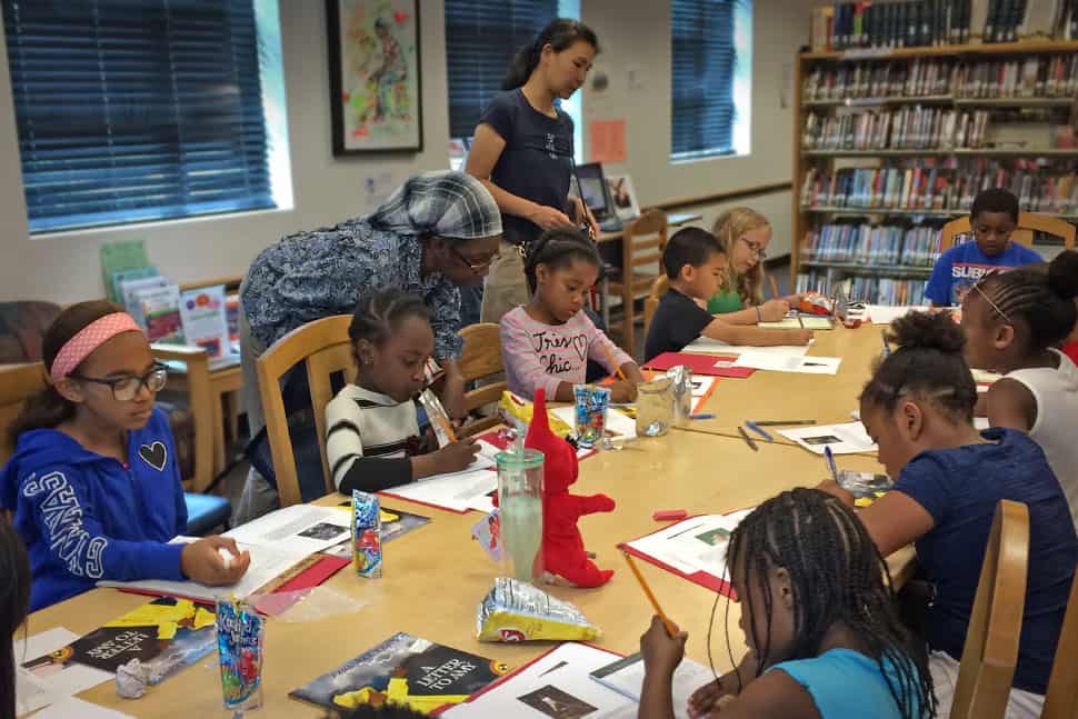 Barbara Prince and YuChieh Chien (standing, from left) assist students in writing their first-draft letters to famous Amys at the Garfield Park Lending Library in New Castle, Delaware.Photo: Sophia Hanson