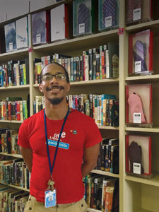 Library assistant Omelio Alexander stands next to the “tiebrary” collection at the Paschalville branch of the Free Library of Philadelphia.