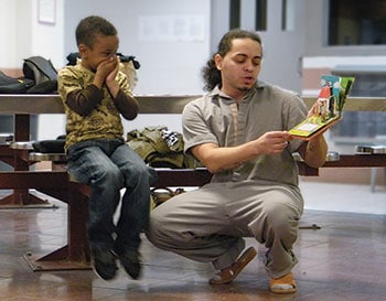 An inmate reads to his son at the Daddy and Me program’s family day event, facilitated at a jail by Brooklyn (N.Y.) Public Library. (Photo: Brooklyn Public Library)