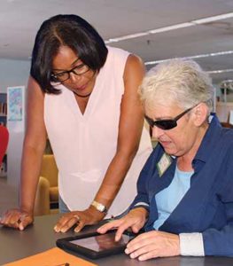 Assistive Technology Specialist Lolly Cheatham, left, trains a patron on the iPad through a New Jersey State Library program for veterans.