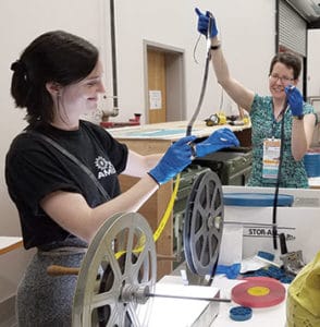 Siobhan Hagan (left), member of the AMIA board of directors, demonstrates rewinding film with the help of preservation volunteer Ann Marie Willer. Photo: Whitney Broadaway