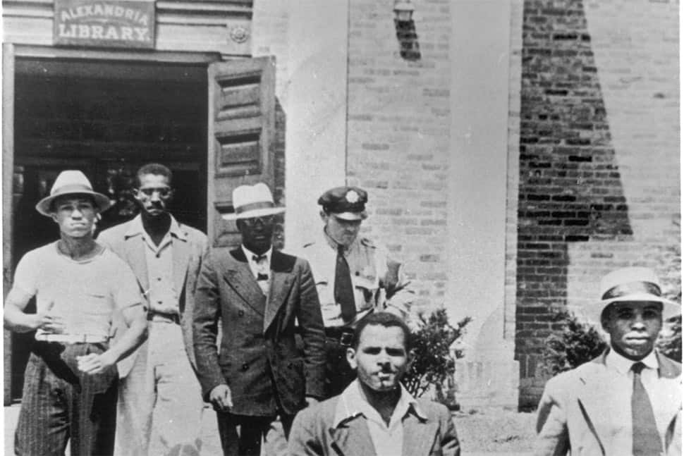 An officer escorts five men from the Alexandria (Va.) Library in August 1939. They were arrested and charged with disorderly conduct.