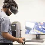 NCSU student Bharat Karunakaran plays Job Simulator with an Oculus Rift headset in Hill Library's VR Studio.