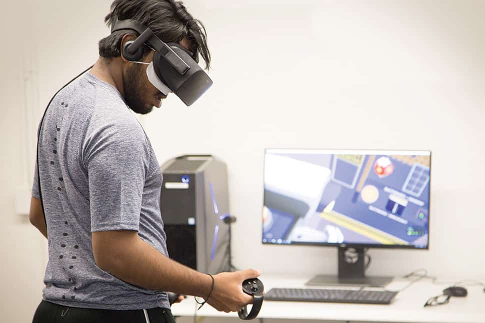 NCSU student Bharat Karunakaran plays Job Simulator with an Oculus Rift headset in Hill Library's VR Studio.
