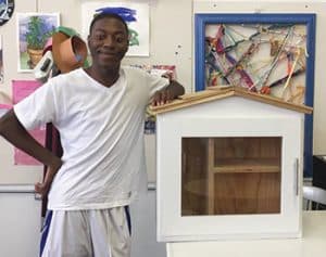 Artist Wayne Pace poses next to a Little Free Library before painting it as part of the Little Library Prize competition at the 2017 Michigan State Fair. <span class="credit">Photo: Detroit Little Libraries</span>