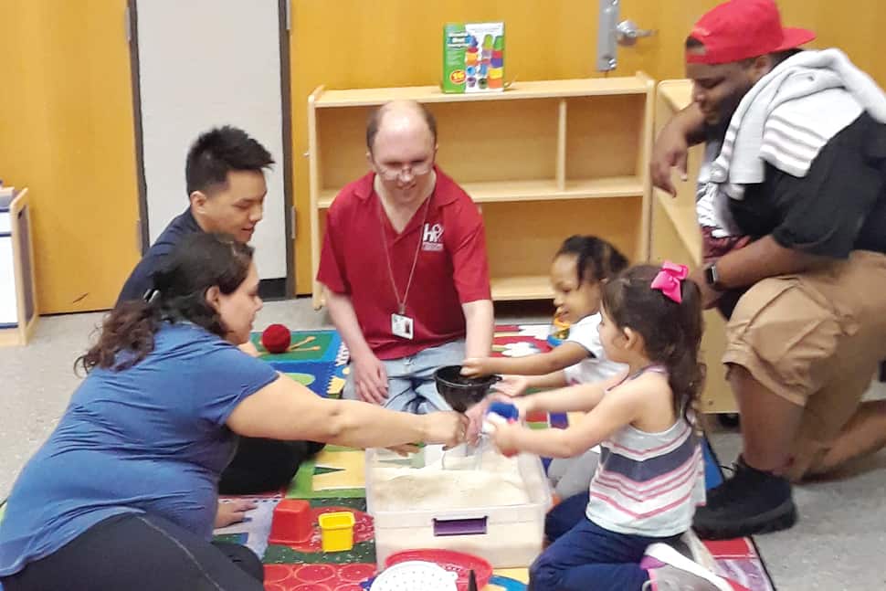 Drew Alvey (in red shirt), manager of Houston Public Library's Stimley–Blue Ridge branch, models interactive play for families. Photo: Houston Public Library