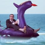 Ron Charles is wearing a full suit sitting on an inflatable dragon pool toy.