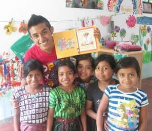 Salvador Isaías Sisay Tuch, coordinator of programs for La Biblioteca Móvil, poses with children served by the traveling library.