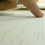 Fingertips reading a Braille manuscript