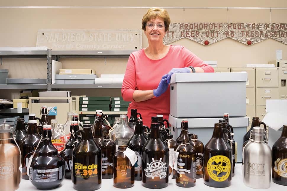 Judith A. Downie poses with growlers from CSUSM Library’s Brewchive. Photo: Brandon Van Zanten (Brewchive)