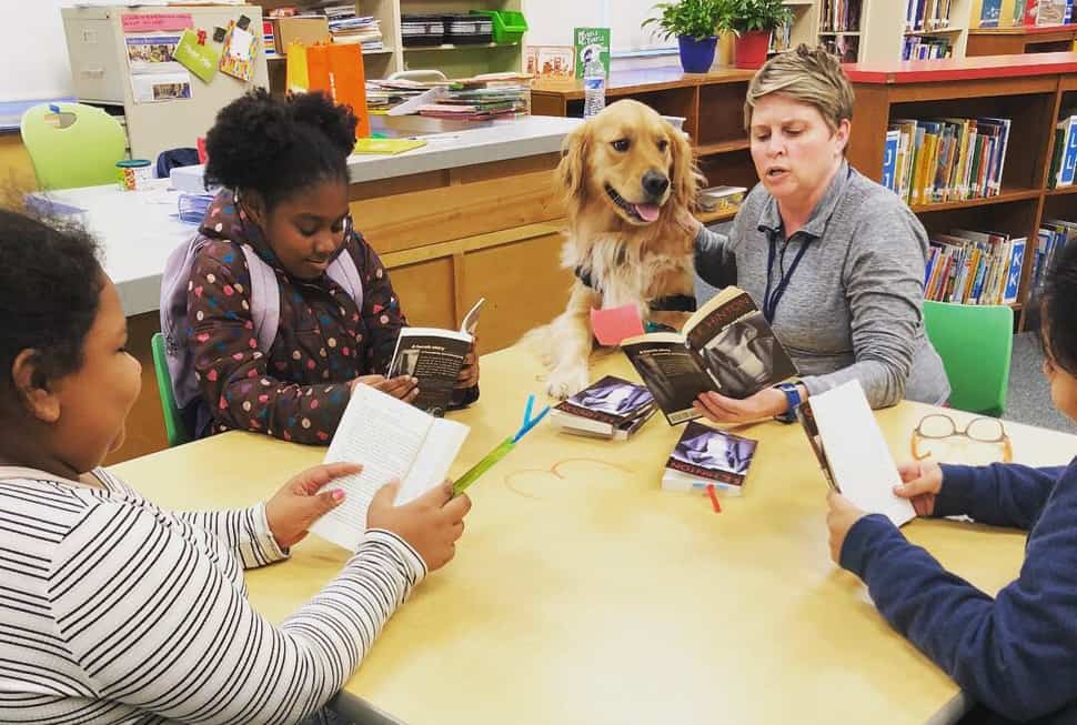 Kerri Price, a Charleston County (S.C.) Teacher Librarian Cohort member in University of South Carolina's Library Scholar program, works with students in her school library, alongside her therapy dog, Bailey.