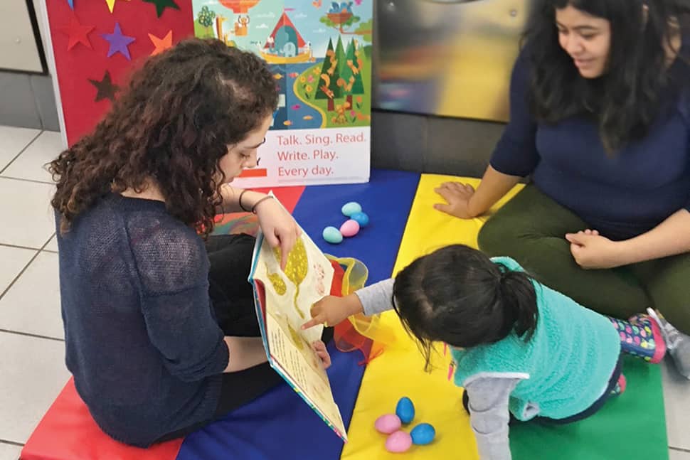 Chicago Public Library STEAM Team First Assistant Librarian Alejandra Santana (left) reads to storytime attendees at Bubbleland laundromat.Photo: Chicago Public Library
