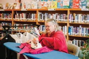 Sandra Vardell, former board member at Jane Morgan Memorial Library in Cambria, Wisconsin, volunteers one Saturday per month to tackle the town's tailoring. Photo: Katie Hunt Photography