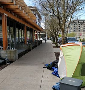 A tent sits outside of Seattle Public Library’s Ballard branch. The library installed exterior metal bars to discourage loitering. (Photo: Alanna Ho)