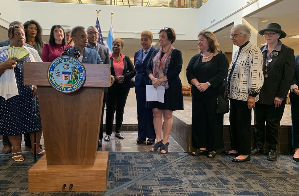 Chicago Mayor Lori Lightfoot (behind podium) announces the elimination of late fees throughout the Chicago Public Library system on September 30 at Woodson Regional Library with CPL Commission Andrea Telli (center, holding paper) and American Library Association Executive Director Mary Ghikas (right). (Photo: Stephanie Hlywak/American Library Association)