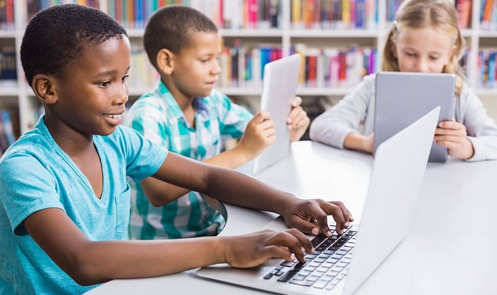 Children use laptops and tablets in a library