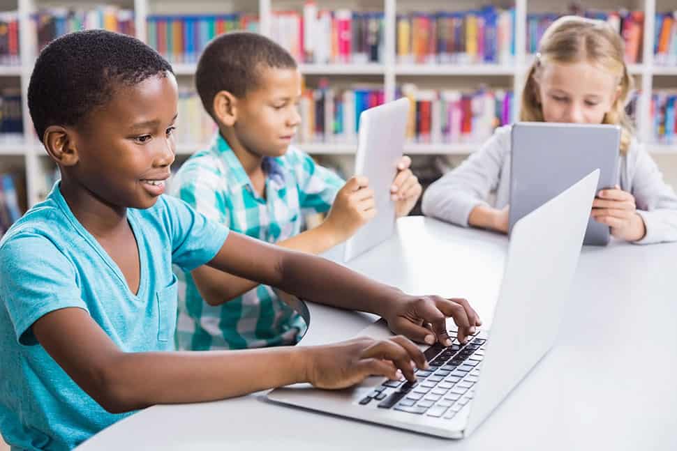 Children use laptops and tablets in a library
