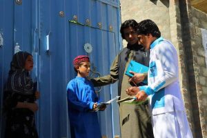 Idress Siyawash (right) distributes books to children