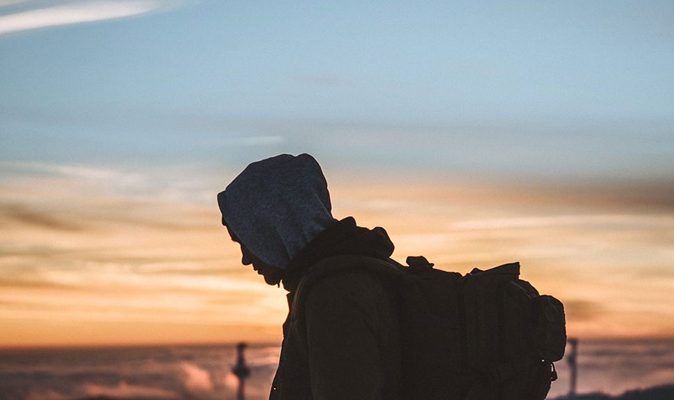 Photo: Silhouette of man with backpack against sunset