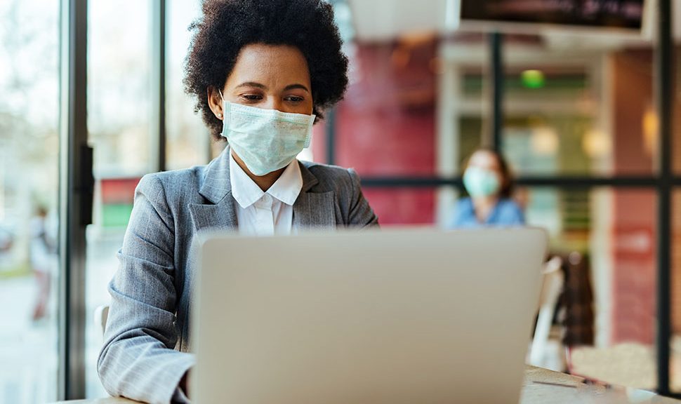 Woman wearing a face mask with a laptop