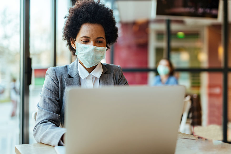 Woman wearing a face mask with a laptop