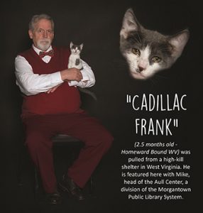 Librarian in red vest poses with kitten named Cadillac Frank