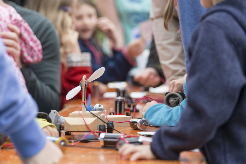 Students build inventions around a shared table