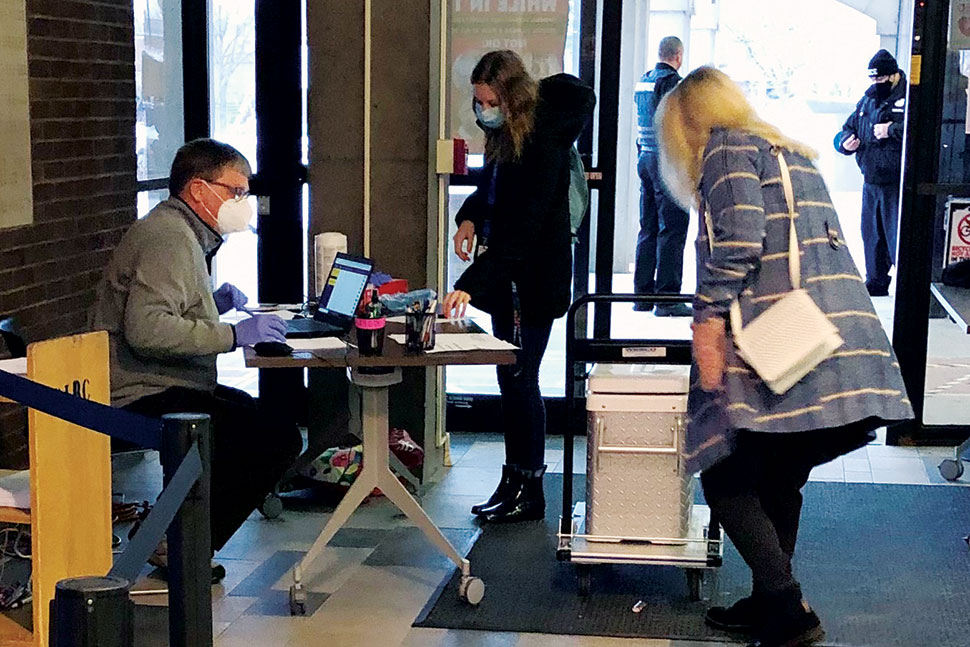 A health care worker from Schenectady County (N.Y.) Public Health Services (right) wheels in the vaccine while David Bradley (left), a member of Friends of the Schenectady County Public Library (SCPL) and spouse of SCPL Director Karen Bradley, checks in vaccine recipients. Photo: Karen Bradley