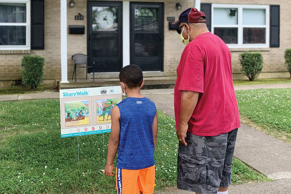 Henderson County (Ky.) Public Library’s StoryWalk participants read a page from picture book Jonathan and His Mommy last summer.