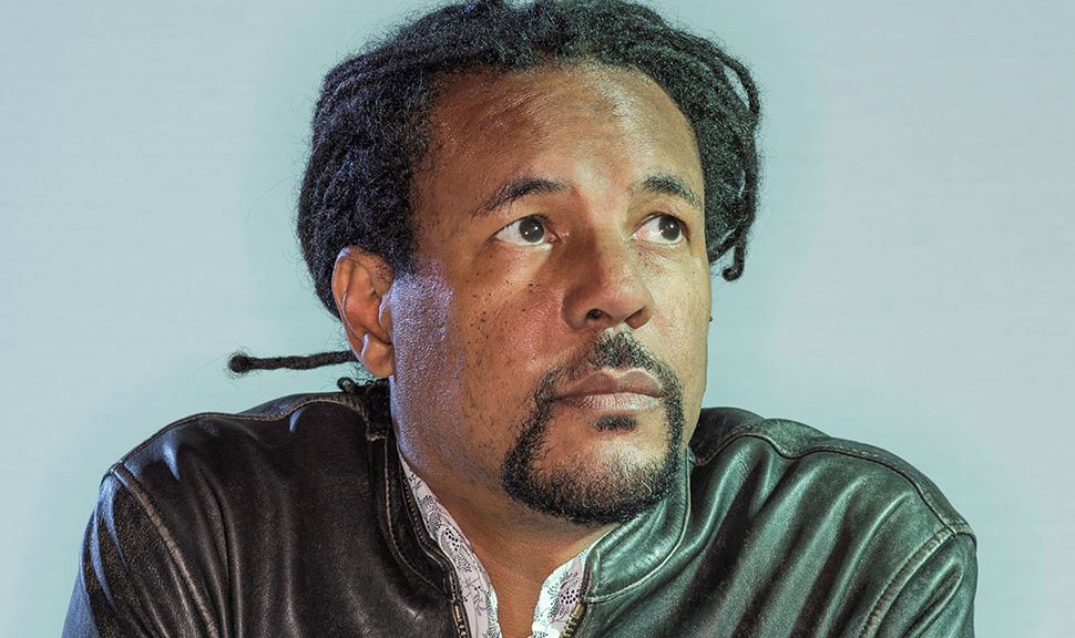 Colson Whitehead (Black man with braided hair pulled back, wearing leather jacket, looking just up and to the right)