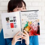 Young woman in blue shirt reads the 10th edition of ALA's Intellectual Freedom Manual