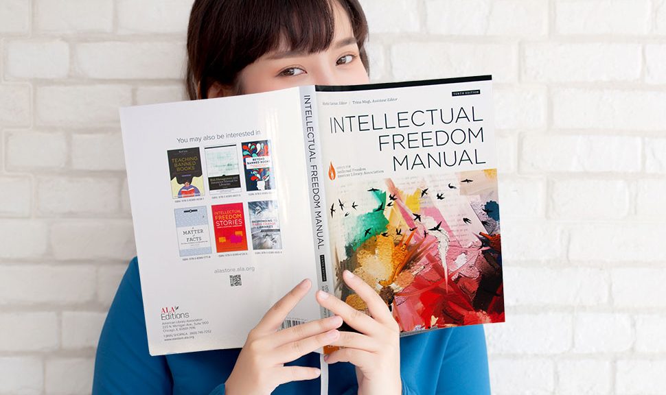 Young woman in blue shirt reads the 10th edition of ALA's Intellectual Freedom Manual