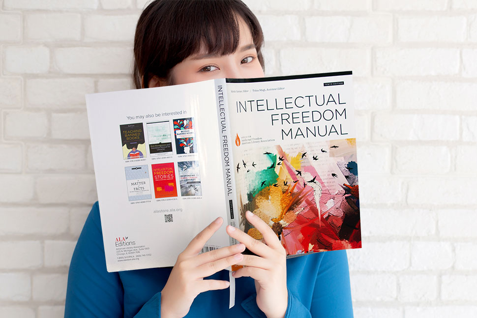 Young woman in blue shirt reads the 10th edition of ALA's Intellectual Freedom Manual