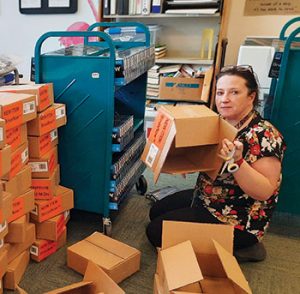 Library Assistant Claire Cassidy loads boxes of BinaxNOW COVID- 19 testing kits onto a cart at South Coastal Library in Bethany Beach, Delaware.